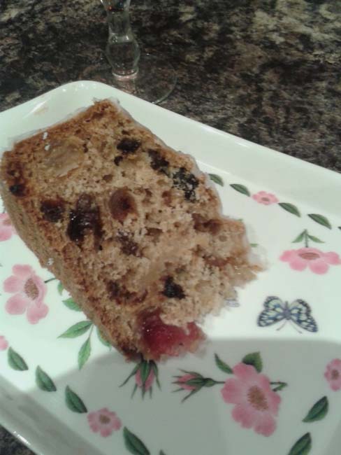 Slide of vinegar cake lade on a floral tray so you can see the fruit evenly patterned throughout, with a particularly delicious cherry that would go in the first bite.